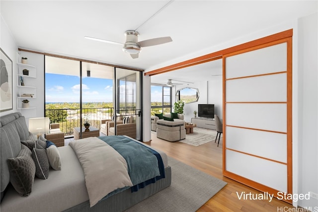 bedroom with light hardwood / wood-style flooring, access to exterior, a wall of windows, and ceiling fan