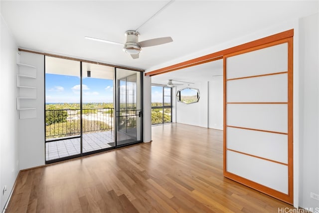 spare room featuring light hardwood / wood-style floors, a wall of windows, and ceiling fan