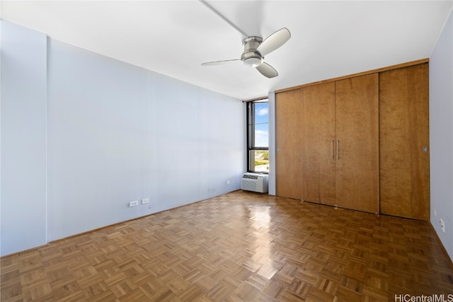 unfurnished bedroom featuring a wall mounted AC, dark parquet flooring, and ceiling fan