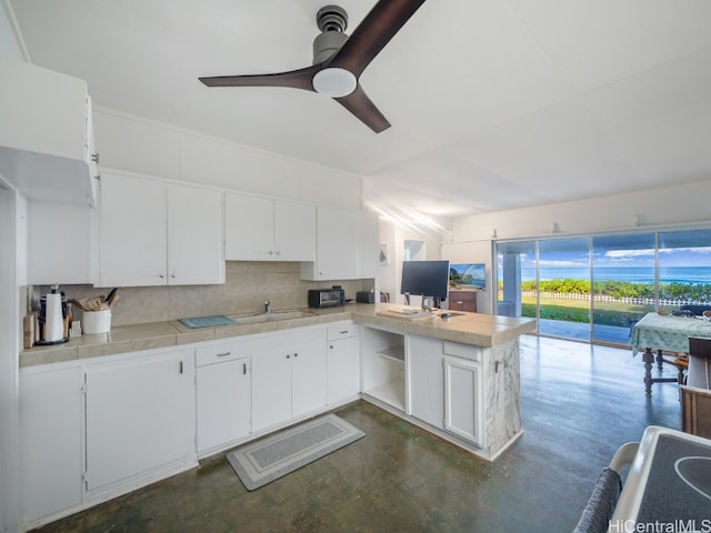 kitchen with backsplash, kitchen peninsula, white cabinetry, ceiling fan, and tile counters