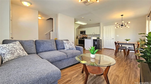 living room featuring sink, light hardwood / wood-style flooring, and a notable chandelier