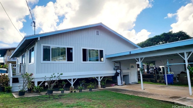 rear view of house featuring a lawn and a carport