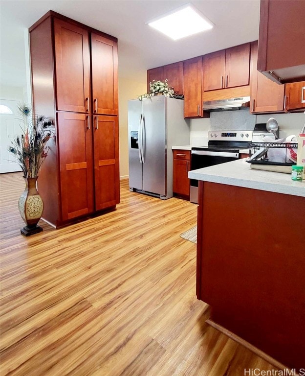 kitchen with range hood, appliances with stainless steel finishes, and light wood-type flooring