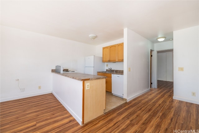 kitchen with kitchen peninsula, dark hardwood / wood-style flooring, white appliances, and sink