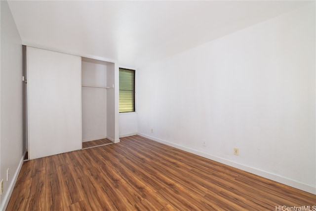 unfurnished bedroom with dark wood-type flooring and a closet