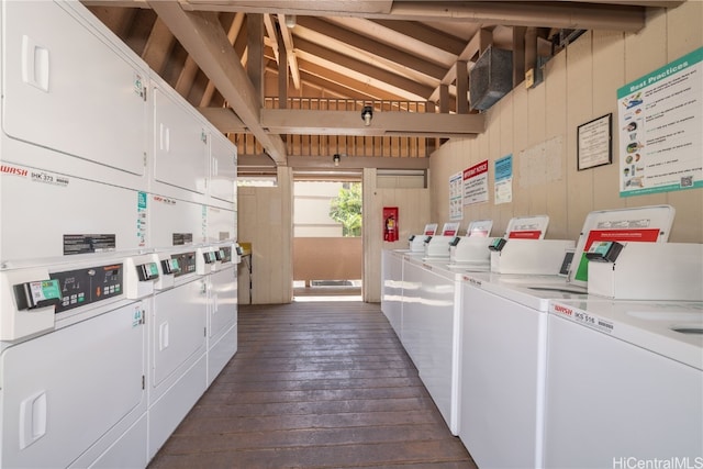 laundry room with dark hardwood / wood-style flooring, washer and clothes dryer, stacked washer and clothes dryer, and wood walls