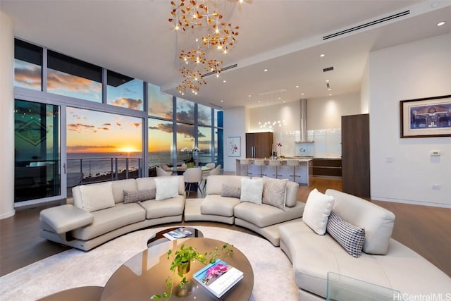 living room featuring a chandelier, hardwood / wood-style floors, a water view, and a wall of windows