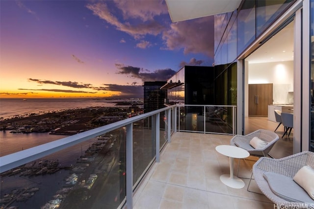 balcony at dusk featuring a water view