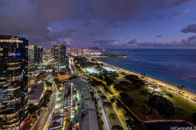 aerial view at dusk with a water view and a view of the beach