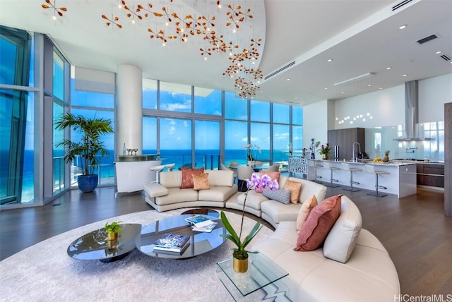 living room with dark hardwood / wood-style floors, a water view, a towering ceiling, and a wall of windows