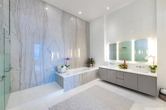 bathroom featuring tile patterned floors, separate shower and tub, vanity, and tile walls