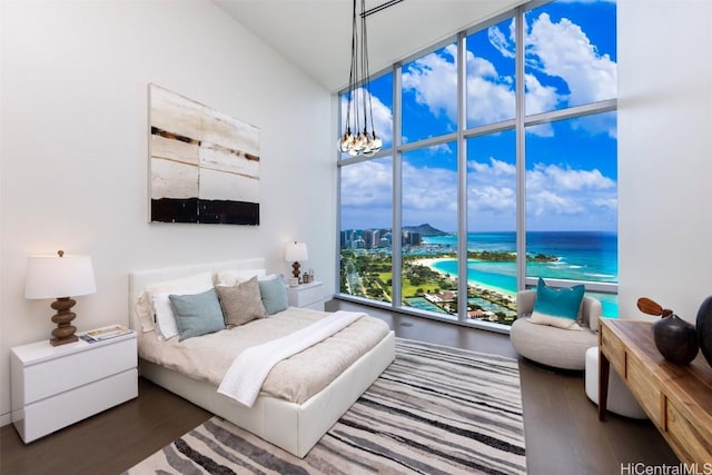 bedroom with a notable chandelier, dark hardwood / wood-style flooring, and a water view