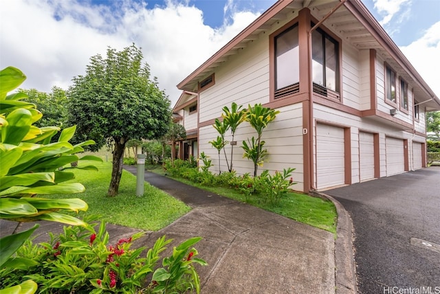 view of side of property featuring a garage and a lawn