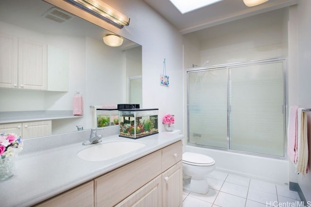 full bathroom with vanity, bath / shower combo with glass door, toilet, and tile patterned flooring