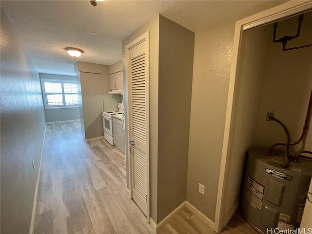 corridor with light hardwood / wood-style flooring, electric water heater, and a textured ceiling