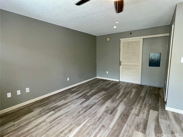 unfurnished bedroom with hardwood / wood-style flooring, a closet, electric panel, a textured ceiling, and ceiling fan