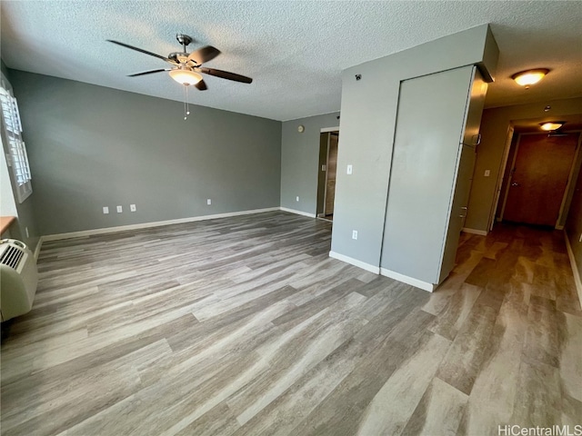 empty room featuring ceiling fan, a textured ceiling, and light wood-type flooring