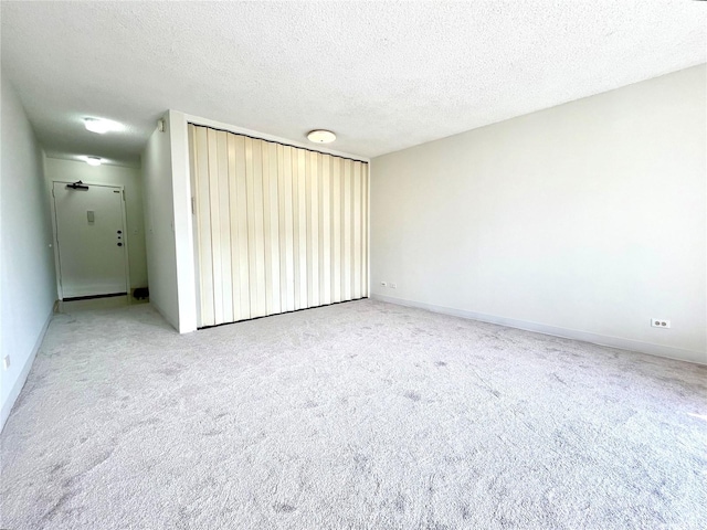 carpeted empty room featuring baseboards and a textured ceiling