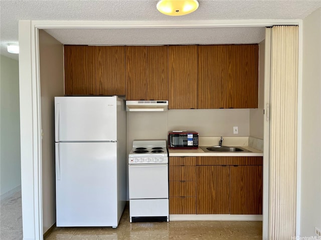 kitchen with white appliances, under cabinet range hood, light countertops, brown cabinets, and a sink