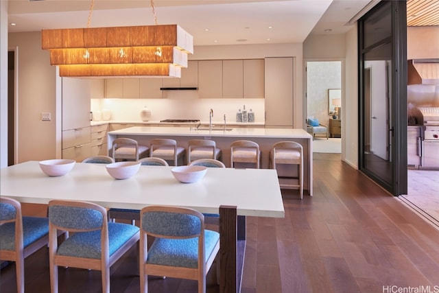 kitchen featuring a center island with sink, sink, dark hardwood / wood-style floors, a breakfast bar area, and gas stovetop