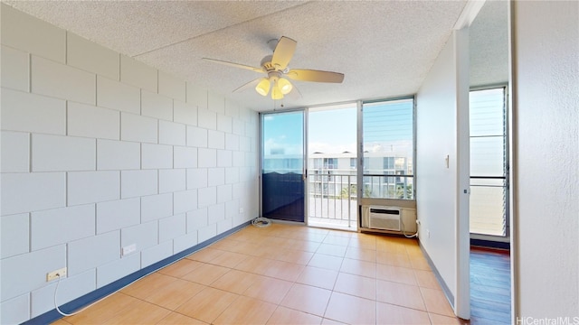 spare room featuring ceiling fan, an AC wall unit, a textured ceiling, and plenty of natural light