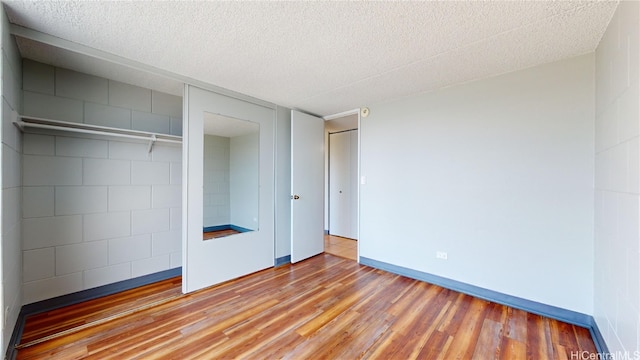 unfurnished bedroom with a closet, a textured ceiling, and hardwood / wood-style floors