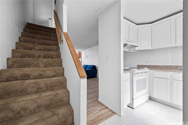 stairs with a textured ceiling and hardwood / wood-style flooring