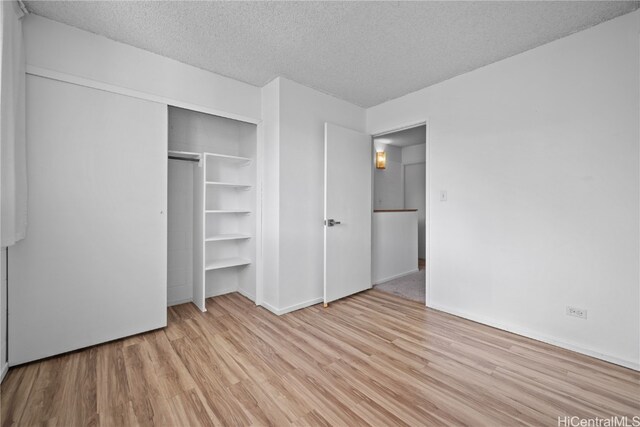 unfurnished bedroom with a closet, a textured ceiling, and light hardwood / wood-style floors