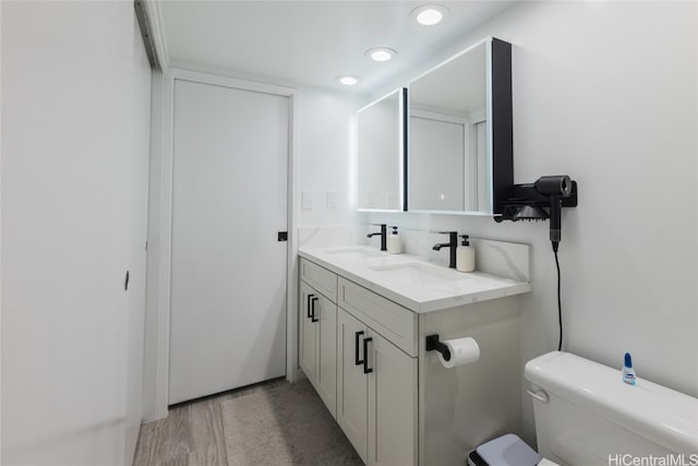 bathroom featuring toilet, hardwood / wood-style flooring, and vanity