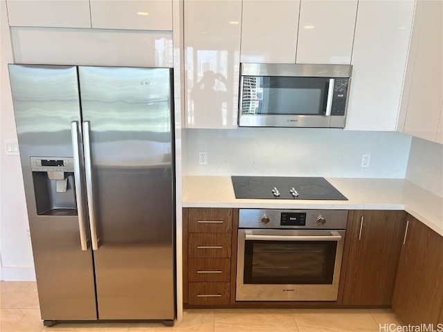 kitchen featuring white cabinetry, backsplash, stainless steel appliances, dark brown cabinetry, and light tile patterned flooring