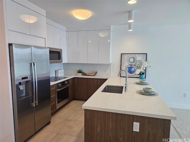 kitchen featuring dark brown cabinetry, sink, white cabinetry, appliances with stainless steel finishes, and kitchen peninsula