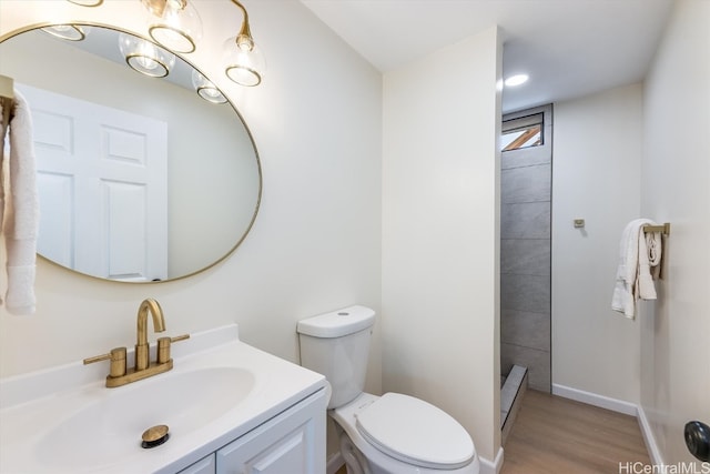 bathroom with toilet, hardwood / wood-style flooring, vanity, and a tile shower