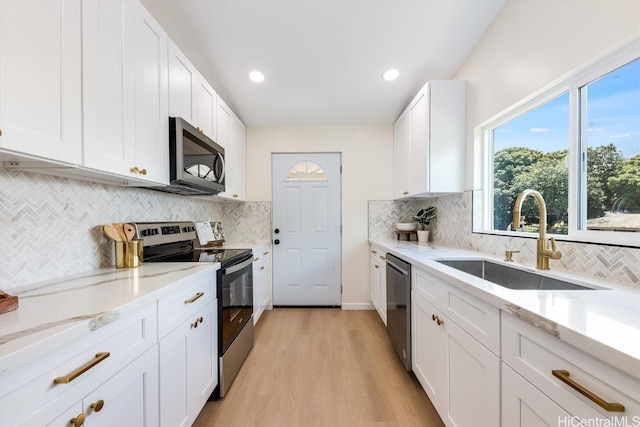 kitchen featuring backsplash, white cabinetry, light hardwood / wood-style flooring, sink, and stainless steel appliances