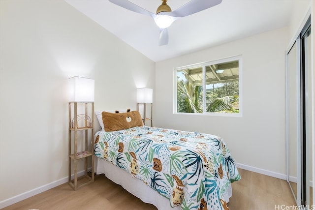 bedroom featuring lofted ceiling, a closet, light hardwood / wood-style floors, and ceiling fan