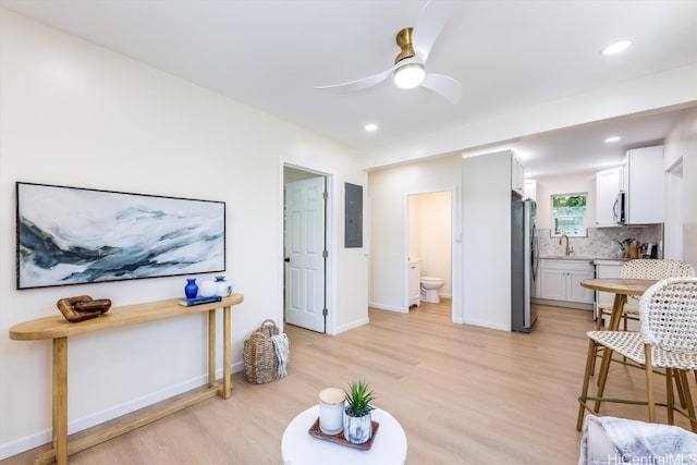 living room with light hardwood / wood-style floors, electric panel, and ceiling fan