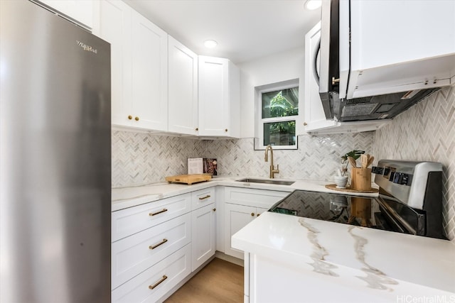 kitchen featuring white cabinetry, light wood-type flooring, stainless steel appliances, sink, and light stone counters