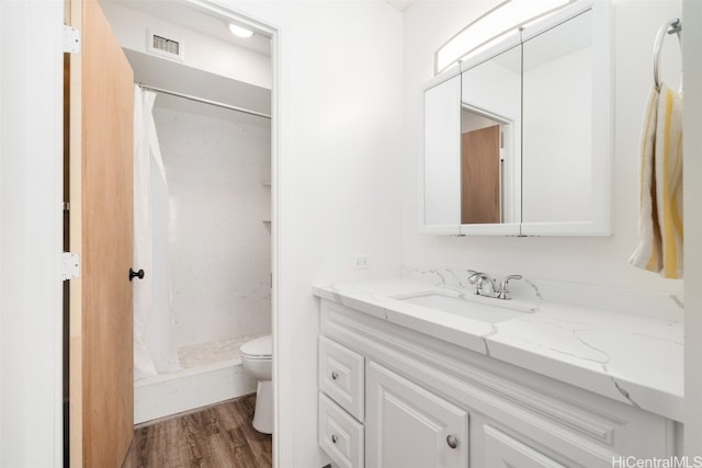 bathroom featuring vanity, curtained shower, wood-type flooring, and toilet