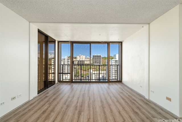 empty room featuring light hardwood / wood-style floors, a textured ceiling, and floor to ceiling windows