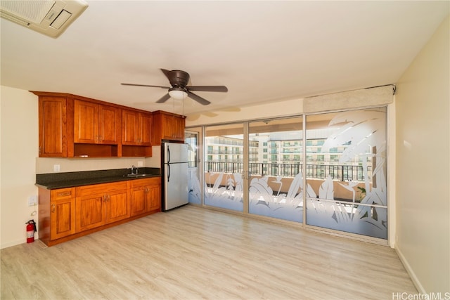 kitchen featuring sink, ceiling fan, light hardwood / wood-style floors, and stainless steel refrigerator