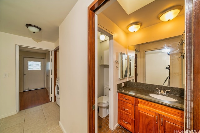 bathroom with vanity, toilet, tile patterned floors, and washer / dryer