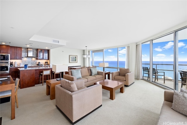 carpeted living room featuring a healthy amount of sunlight, a water view, and floor to ceiling windows