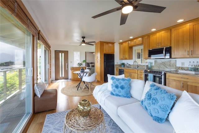 living room with ceiling fan, light wood-type flooring, and sink