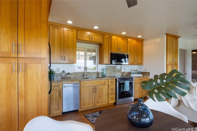 kitchen with dark hardwood / wood-style flooring, light stone countertops, sink, and appliances with stainless steel finishes