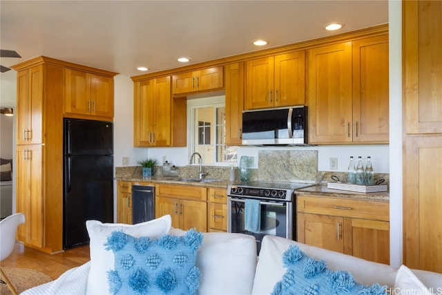 kitchen with sink, light stone counters, black refrigerator, stainless steel range with electric cooktop, and light wood-type flooring