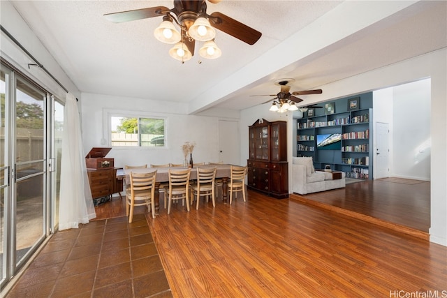 dining room featuring beam ceiling, dark wood-type flooring, a textured ceiling, and ceiling fan