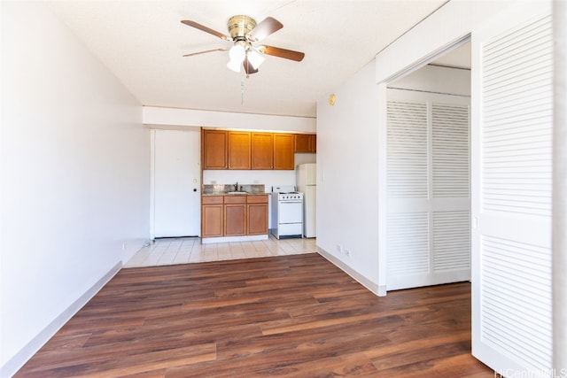 kitchen featuring white appliances, sink, a textured ceiling, ceiling fan, and light hardwood / wood-style flooring