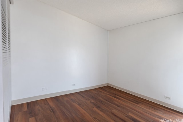 spare room featuring a textured ceiling and dark hardwood / wood-style flooring