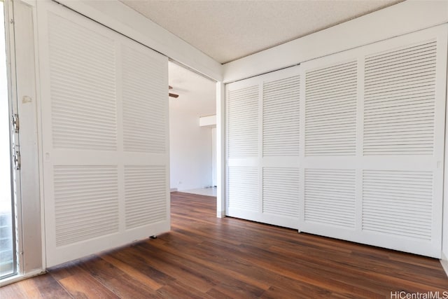 unfurnished bedroom featuring a textured ceiling and dark hardwood / wood-style flooring