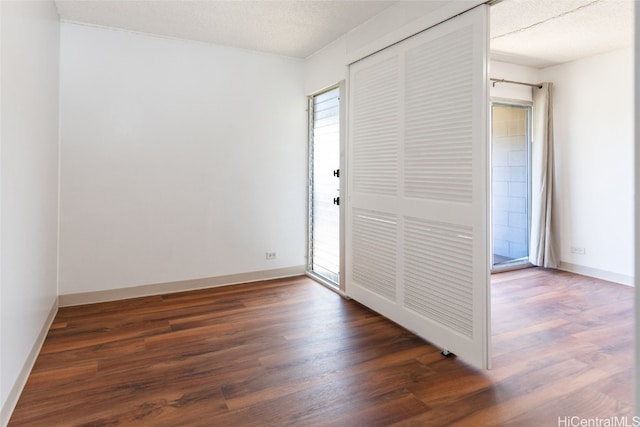 unfurnished bedroom with dark wood-type flooring, a textured ceiling, and a closet