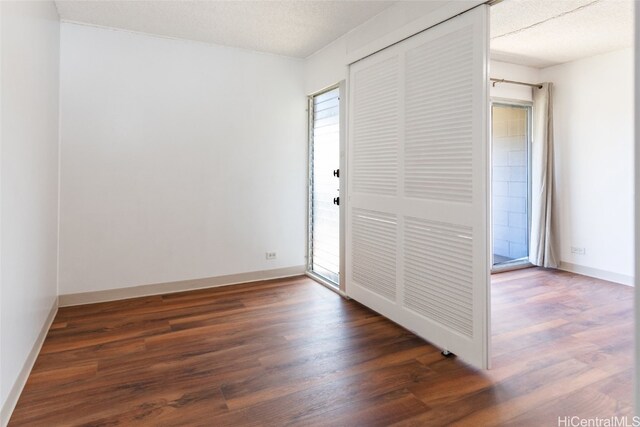 unfurnished room with a textured ceiling, baseboards, and wood finished floors